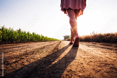 Fotomural woman goes barefoot at sunset on field road