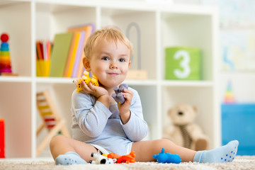 little child boy plays with toys animals