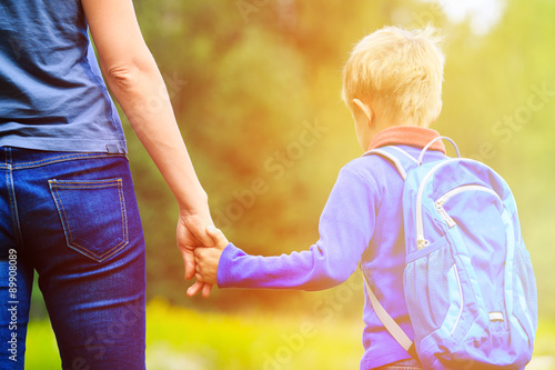 Fotografia, Obraz Mother holding hand of little son with backpack outdoors