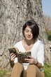 Beautiful young woman reading a book on tree background