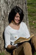 Beautiful young woman reading a book on tree background