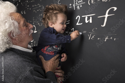 Fotografia Nonno scienziato con nipotino in braccio che scrive alla lavagna