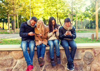 Poster - smiling friends with smartphones in city park