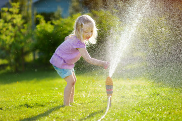 Canvas Print - Adorable little girl playing with a sprinkler