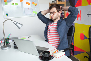 Stressed young male in modern office with laptop