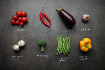 Fresh vegetables with chalky signs on grey kitchen table