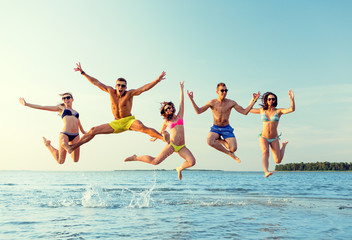 Wall Mural - smiling friends in sunglasses on summer beach