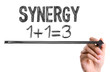 Hand with marker writing the word Synergy 1+1=3