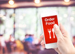 © weedezign - Hand holding mobile with Order food with blur restaurant backgro