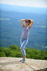 Young woman posing at the edge of rock at Minnewaska State Park Reserve Upstate NY during summer time