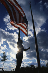 Wall Mural - This is a Park Ranger, raising the American flag on its flagpole. He is silhouetted, arm reaching up against a blue sky with clouds.