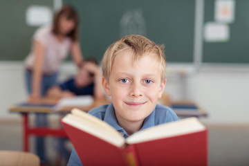 Poster - glücklicher junge in der schule mit einem buch