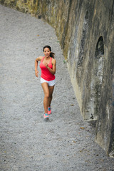 Wall Mural - Female fit hispanic athlete running outdoor. Sporty cheerful woman training.