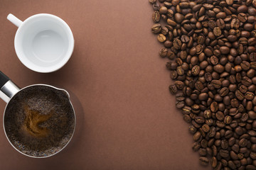 Pot of coffee, beans and white empty cup on brown background