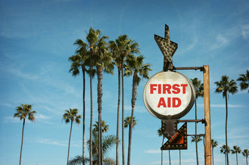 Wall Mural - aged and worn vintage photo of first aid sign on beach with palm trees