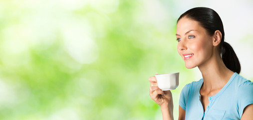 Wall Mural - Young happy smiling woman drinking coffee, outdoors