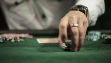 Casino: Man playing poker, excited, turns casino tokens in hand. Close up, slow motion