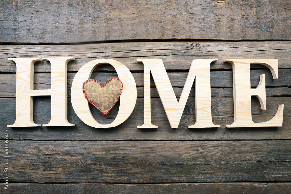 Decorative letters forming word HOME with heart on wooden background