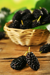 Poster - Fresh mulberry in wicker basket on wooden table, closeup