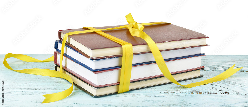 Stack of books with ribbon on table isolated on white