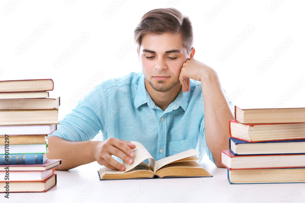 Young man reading book at table on white background