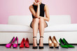 Woman thinking on the sofa with many shoes.Beautiful colorful high heels. 