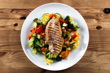 Grilled Chicken Fillet, Breast With Cooked Vegetable Tomatoes, Carrots, Peppers, Courgettes, Brocoli On Plates.