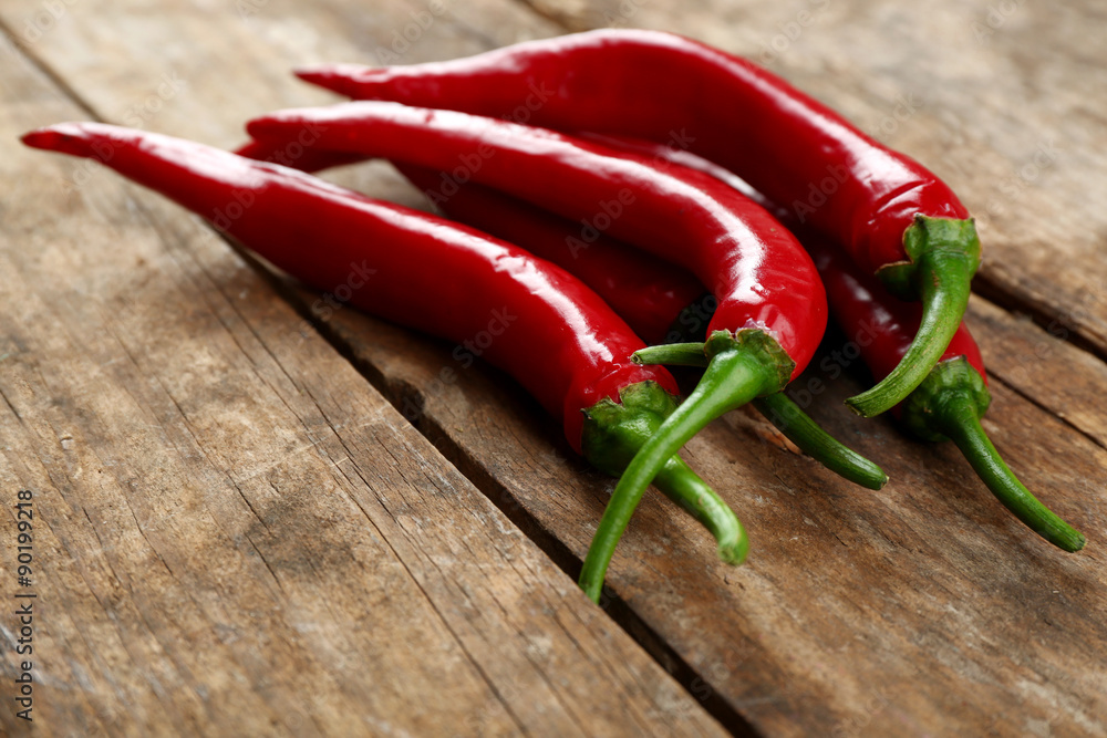 Red hot peppers on wooden table close up