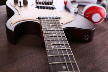 Electric guitar with headphones on wooden table close up