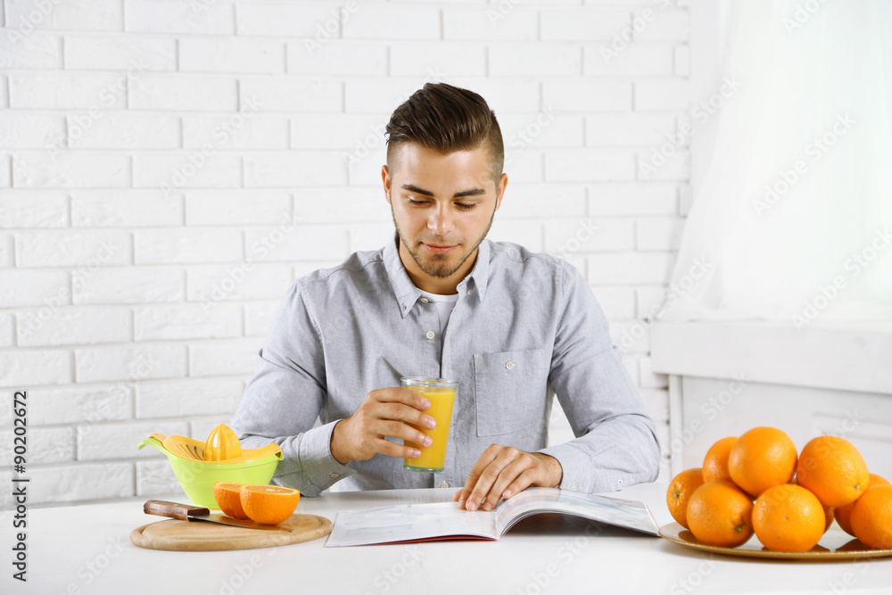 Young man having a table full of fresh oranges and juice