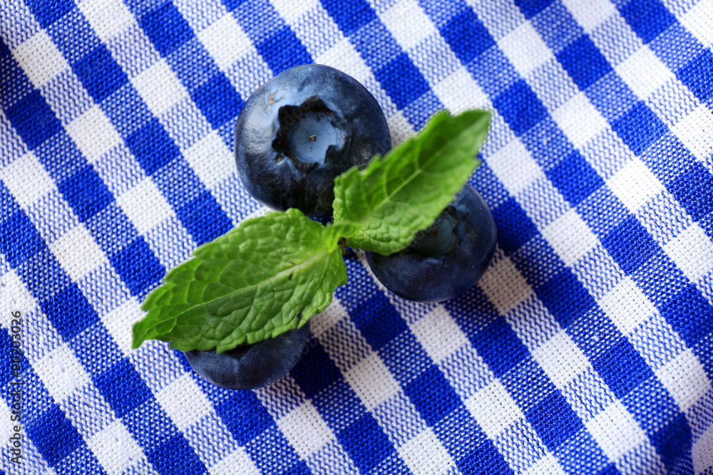 Tasty ripe blueberries with mint on fabric background