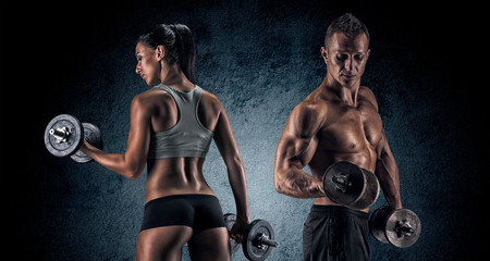 Wall Mural - Athletic man and woman with a dumbells.