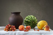 Глиняный кувшин и фрукты: виноград, дыня, арбуз и персики.