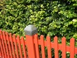 Roter Zaun aus Holz vor grünen Sträuchern im Sommer bei Sonnenschein in Oerlinghausen bei Bielefeld am Hermannsweg im Teutoburger Wald in Ostwestfalen-Lippe