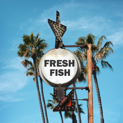 aged and worn vintage photo of fresh fish sign and palm trees