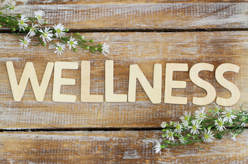 Wall Mural - Wellness written with wooden letters, fresh chamomile flowers on rustic surface
