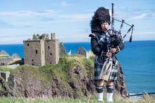 Traditional Scottish Bagpiper In Full Dress Code At Dunnottar Castle In Stonehaven
