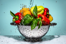 Peppers Of Different Colors In A Colander Under Running Water.