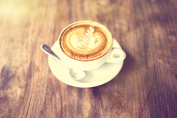 Cup of cappuccino on a wooden table, vintage photo effect