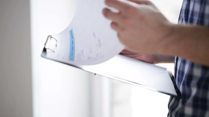 Wall Mural - close up of man looking and writing to clipboard