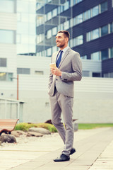 young serious businessman with paper cup outdoors