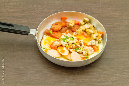 Foto Indochina pan-fried egg with toppings in pan on black wooden