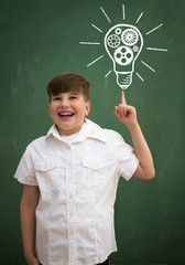 Wall Mural - happy child against blackboard with drawing light bulb idea