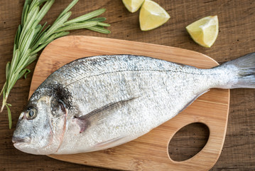 Wall Mural - Fresh dorada with ingredients on the wooden board