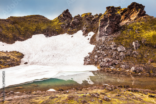 Fotografie, Obraz Big unmelted in July snowfield reflected in water