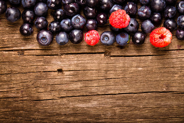 Wall Mural - Forest blueberries and raspberries on an old wooden board