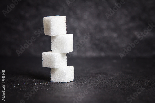 Fotografie, Obraz cloose up white sugar cubes on black stone plate background