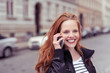 © contrastwerkstatt - lachende frau telefoniert draußen auf der straße