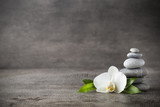White orchid and spa stones on the grey background.