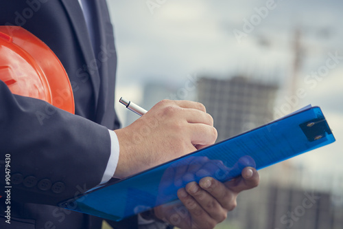 Fotografía Close-up Worker inspector holding clipboard on the background of construction